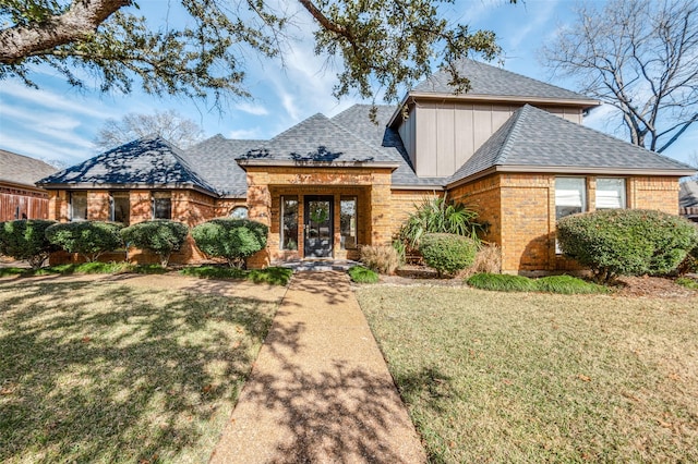 view of front of property featuring french doors, a front lawn, board and batten siding, and brick siding