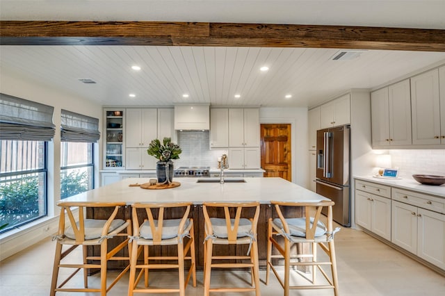 kitchen featuring a breakfast bar, a kitchen island with sink, high quality fridge, and a sink