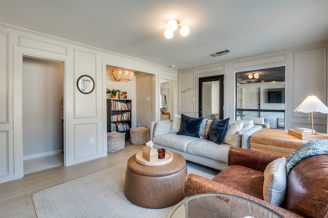 living room with visible vents, a decorative wall, and wood finished floors