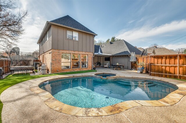 view of pool with a trampoline, a patio area, a fenced backyard, and a pool with connected hot tub