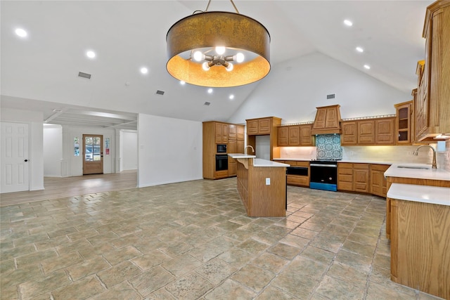 kitchen featuring brown cabinets, visible vents, open floor plan, a sink, and black appliances