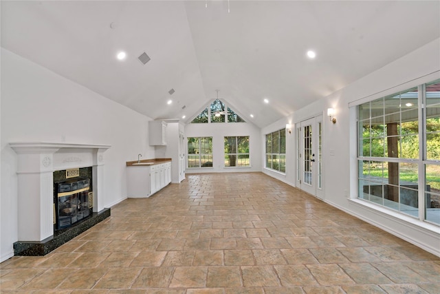 unfurnished living room with visible vents, a high end fireplace, lofted ceiling, a sink, and recessed lighting