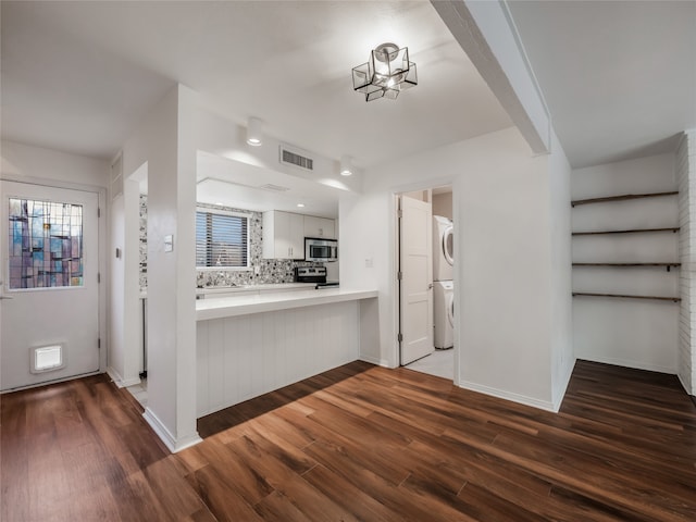 kitchen featuring tasteful backsplash, visible vents, appliances with stainless steel finishes, wood finished floors, and stacked washer / drying machine