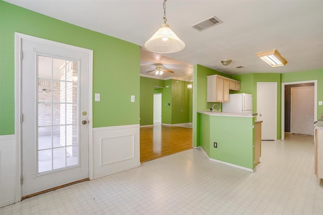 kitchen featuring decorative light fixtures, light countertops, visible vents, freestanding refrigerator, and wainscoting