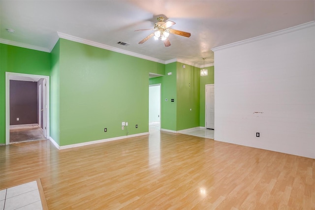 empty room featuring ornamental molding, visible vents, and light wood finished floors