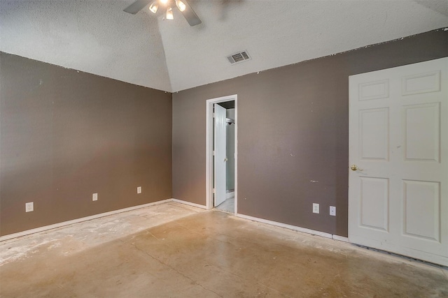 spare room featuring visible vents, ceiling fan, vaulted ceiling, a textured ceiling, and concrete floors