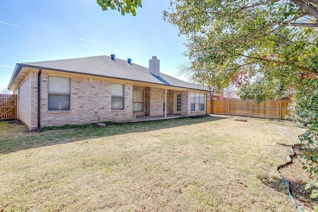 back of house with roof with shingles, brick siding, a yard, a chimney, and a fenced backyard