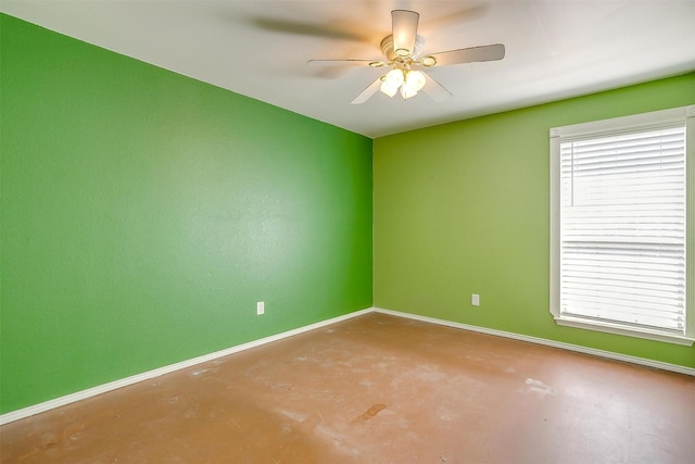 spare room with plenty of natural light, concrete floors, baseboards, and a ceiling fan