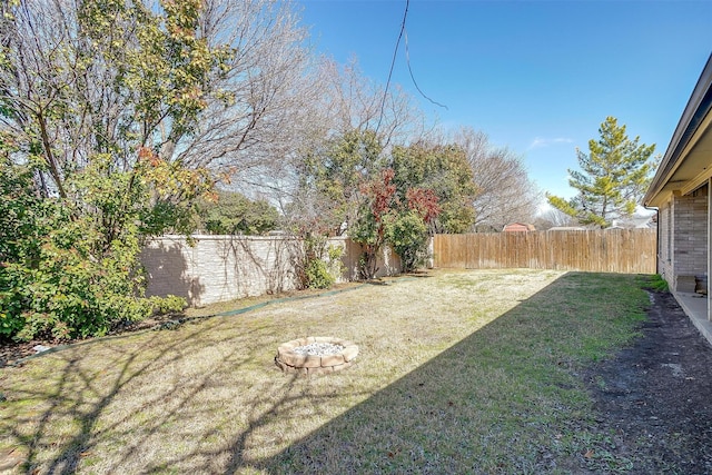 view of yard with a fenced backyard and a fire pit