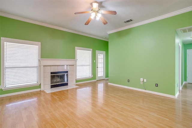 unfurnished living room with crown molding, a fireplace, visible vents, a ceiling fan, and wood finished floors