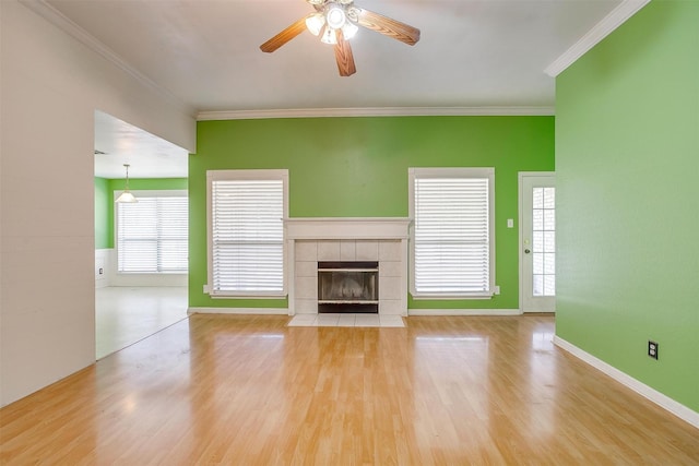 unfurnished living room featuring crown molding, a ceiling fan, wood finished floors, and a tile fireplace