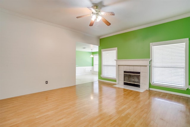 unfurnished living room with a tiled fireplace, ornamental molding, and wood finished floors