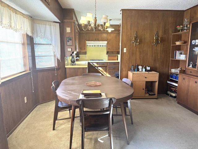 dining room with light colored carpet, wooden walls, and a textured ceiling