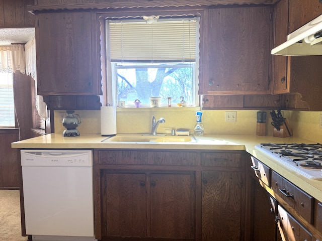 kitchen with light countertops, white appliances, a sink, and under cabinet range hood