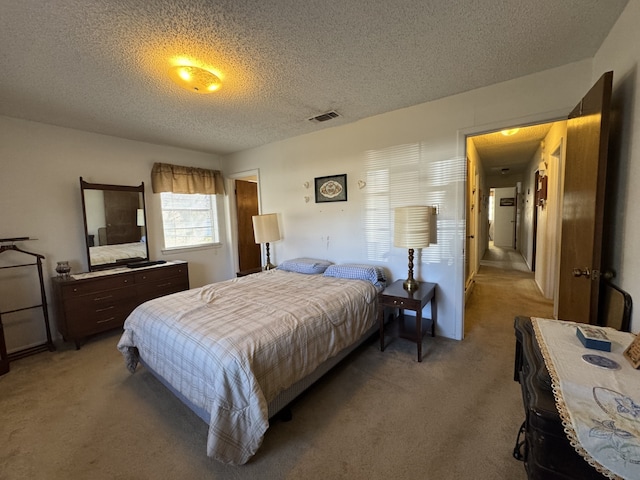 bedroom featuring visible vents, a textured ceiling, and light colored carpet