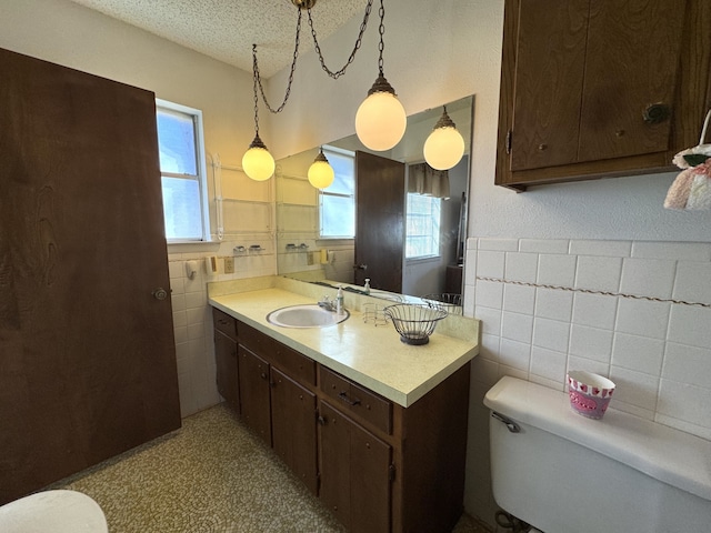 bathroom with plenty of natural light, tile walls, toilet, and a textured ceiling