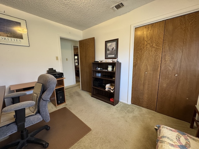 office space with visible vents, light carpet, and a textured ceiling