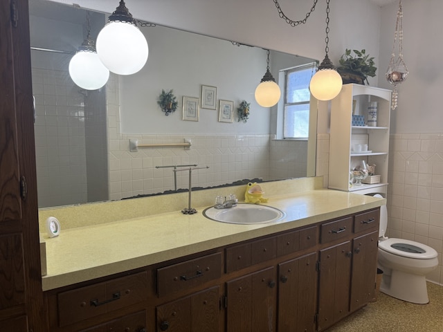 bathroom with toilet, wainscoting, vanity, and tile walls