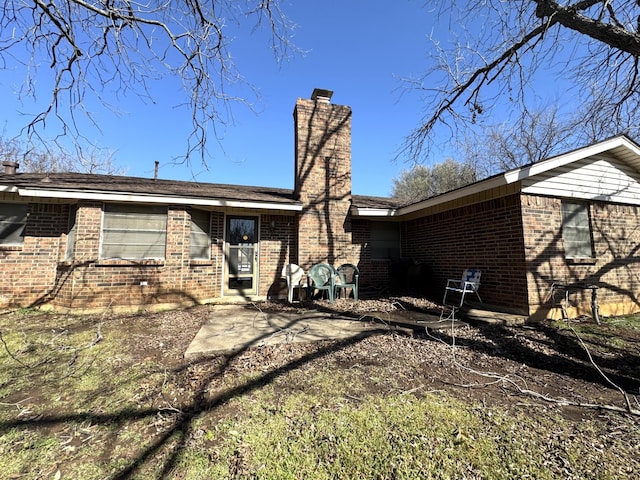 rear view of house with brick siding and a chimney