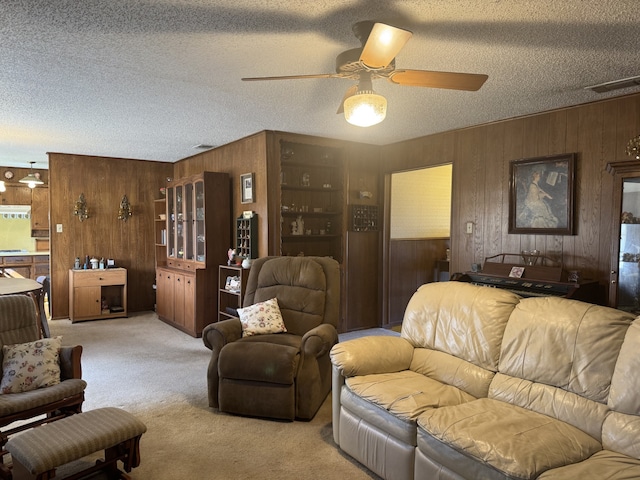 living area with ceiling fan, visible vents, a textured ceiling, and light colored carpet