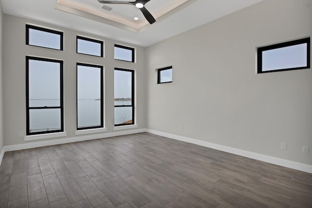 spare room with baseboards, a raised ceiling, dark wood-style floors, ceiling fan, and recessed lighting