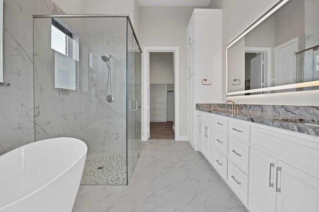 full bath featuring a freestanding tub, vanity, marble finish floor, a spacious closet, and a shower stall