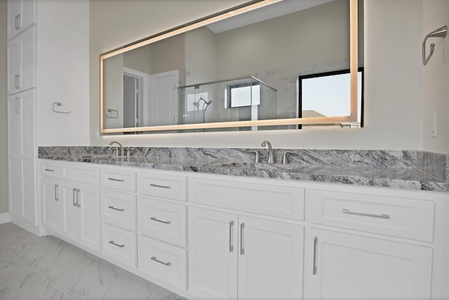 full bathroom featuring double vanity, marble finish floor, a sink, and a stall shower