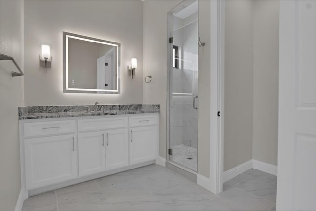 full bathroom featuring marble finish floor, a stall shower, vanity, and baseboards