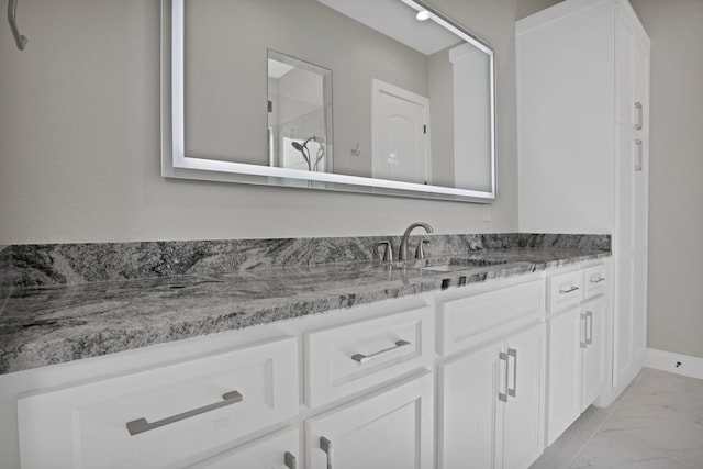 full bathroom with marble finish floor, vanity, and baseboards