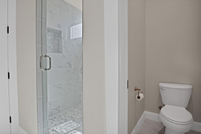 bathroom featuring marble finish floor, a shower stall, toilet, and baseboards