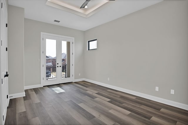 spare room featuring french doors, dark wood-style flooring, a raised ceiling, visible vents, and baseboards