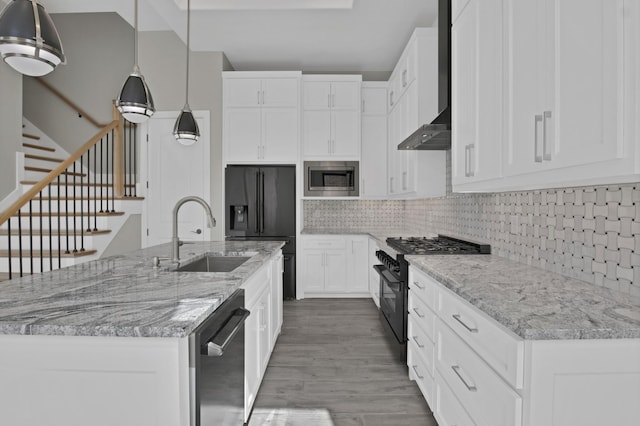 kitchen with a center island with sink, backsplash, wall chimney range hood, black appliances, and a sink