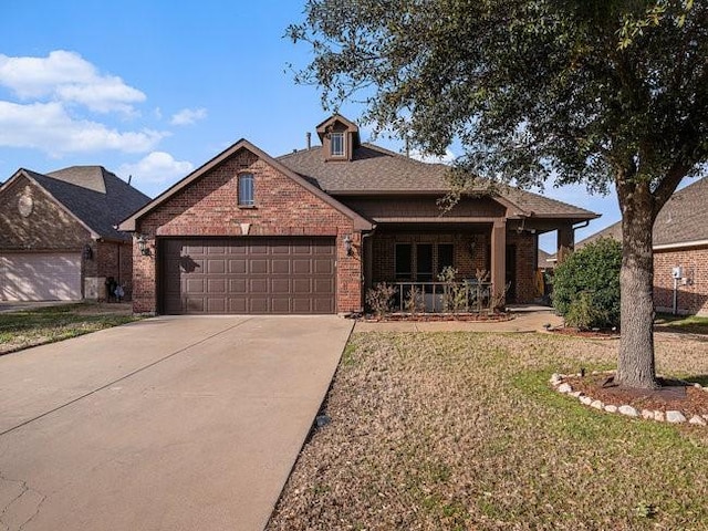 view of front of property with brick siding, covered porch, an attached garage, driveway, and a front lawn