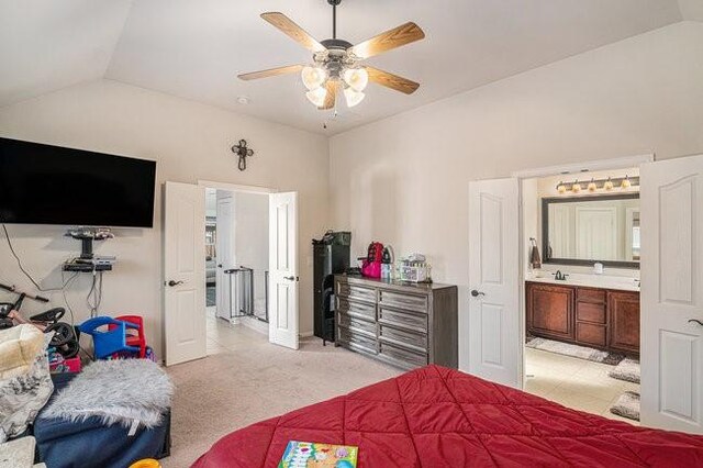 bedroom with a ceiling fan, light carpet, connected bathroom, vaulted ceiling, and a sink