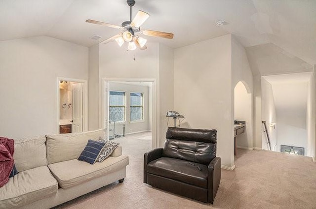 carpeted living area with ceiling fan, arched walkways, vaulted ceiling, and baseboards