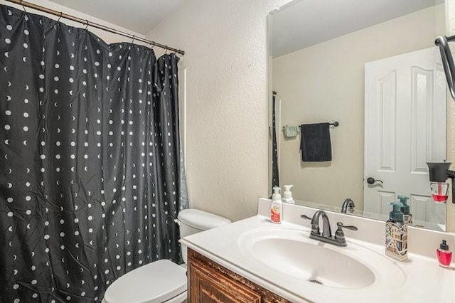 bathroom with toilet, a textured wall, a shower with curtain, and vanity