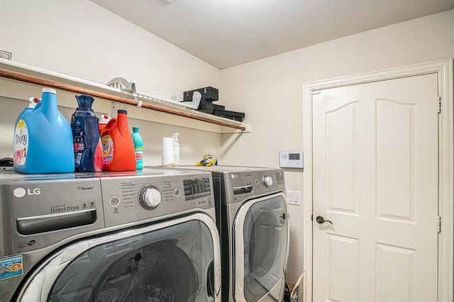 washroom featuring laundry area, a textured ceiling, and separate washer and dryer