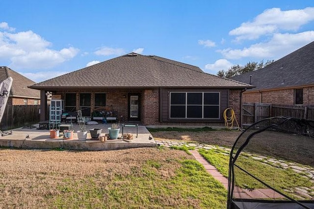 back of house featuring brick siding, a patio, a fenced backyard, and a lawn