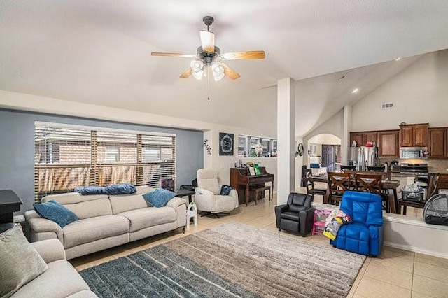 living room with light tile patterned floors, visible vents, arched walkways, a ceiling fan, and high vaulted ceiling