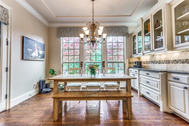 dining area with ornamental molding, an inviting chandelier, dark wood finished floors, and baseboards