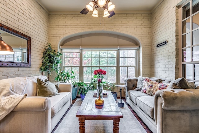 living room featuring a ceiling fan and brick wall