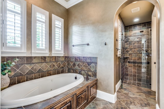 bathroom with ornamental molding, a stall shower, a bath, and baseboards