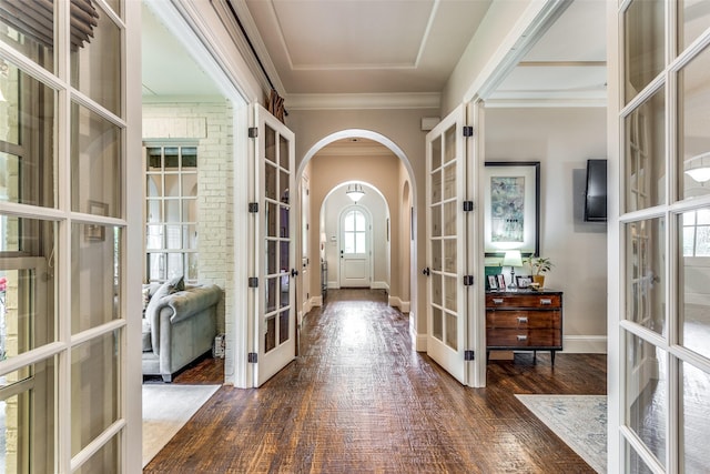 entryway featuring arched walkways, dark wood finished floors, crown molding, and french doors