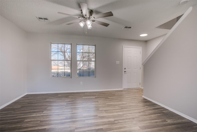 empty room with visible vents, a textured ceiling, baseboards, and wood finished floors