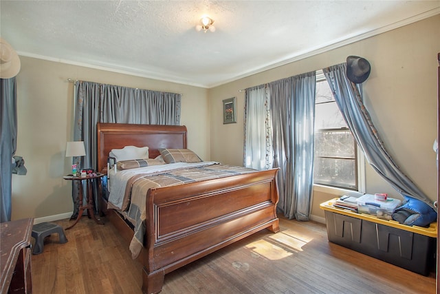 bedroom with a textured ceiling, hardwood / wood-style floors, and baseboards