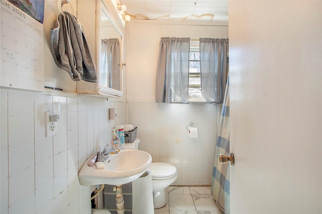 bathroom featuring toilet, marble finish floor, and a sink