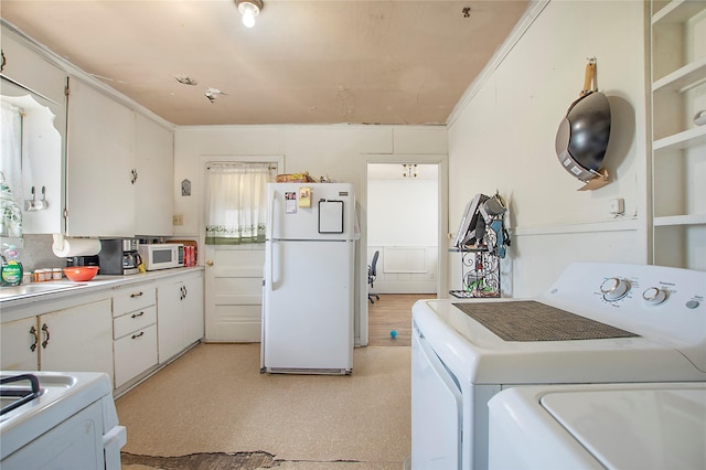 clothes washing area featuring laundry area, crown molding, light floors, washing machine and dryer, and a sink