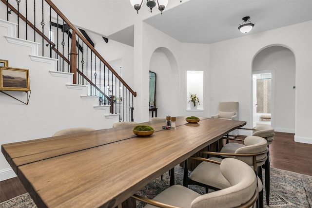 dining room featuring stairs, arched walkways, baseboards, and wood finished floors