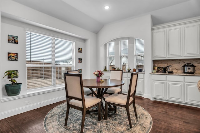 dining area with vaulted ceiling, dark wood finished floors, a wealth of natural light, and baseboards