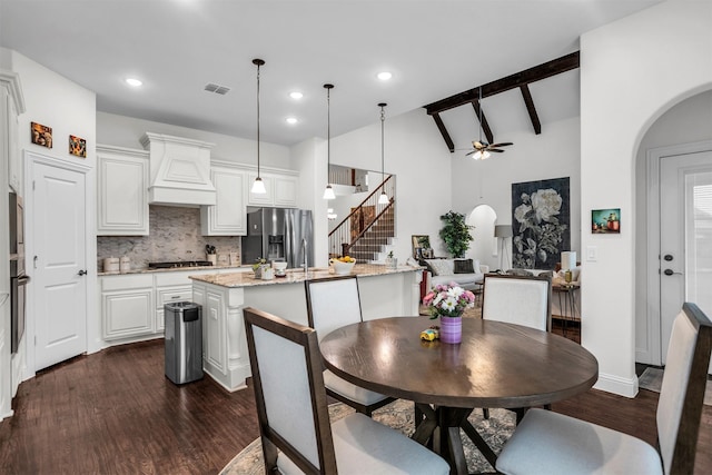 dining area with arched walkways, stairway, dark wood finished floors, and vaulted ceiling with beams